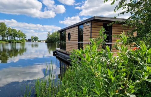 a wooden house on the side of a lake at Houseboat with lake view Tango in Haren
