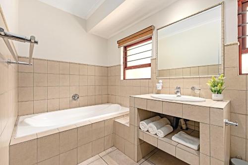 a bathroom with a bath tub and a sink at Shai in Johannesburg