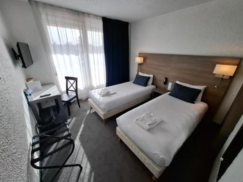 a hotel room with two beds and a desk at Cit'Hôtel Le Quai 9 , ex Le Challans in Challans