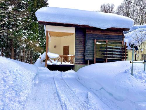 a small house covered in snow next to a pile of snow at 東京2時間スキー場徒歩3分温泉付 友達や家族と一棟貸 in Sudagai