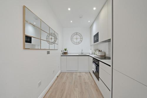 a white kitchen with white cabinets and a wooden floor at Beautiful Victorian Townhouse in London