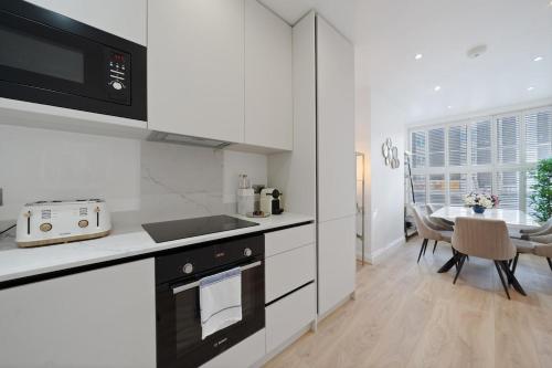 a kitchen with white cabinets and a table with chairs at Beautiful Victorian Townhouse in London
