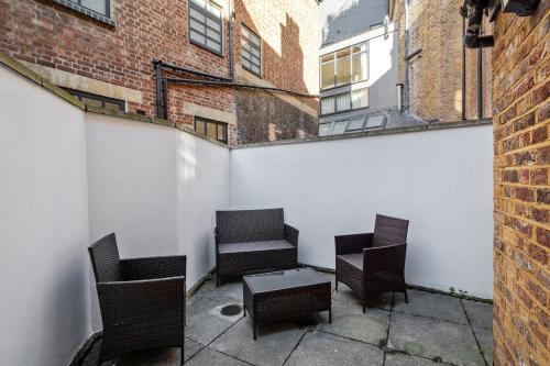 a patio with chairs and a table and buildings at Beautiful Victorian Townhouse in London