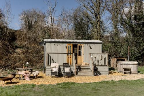 un pequeño cobertizo con gente sentada en sillas delante. en Lambourne Hut By Birch Stays, en Chirk