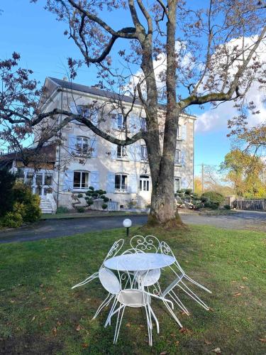 uma mesa e duas cadeiras em frente a uma árvore em Le Moulin Du Port em Saint-Georges-sur-Cher