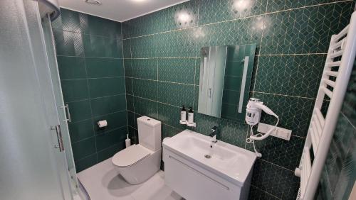 a green tiled bathroom with a toilet and a sink at Suncity Hotel & SPA in Šiauliai