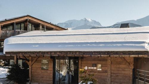 een huis bedekt met sneeuw met bergen op de achtergrond bij L'Alpaga, a Beaumier hotel in Megève