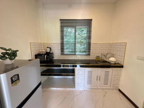 a kitchen with a sink and a refrigerator at Maisuree Lanta Resort-Long Beach in Ko Lanta