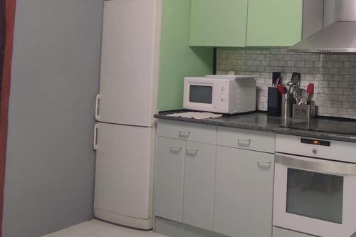 Una cocina con un refrigerador blanco y un microondas. en La torre romana, en Olite