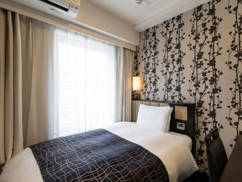 a bedroom with a bed and a window at APA Hotel Kobe Sannomiya in Kobe