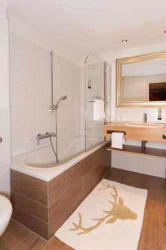 a bathroom with a tub and a toilet and a sink at Hotel garni Reiffenstuel in Rottach-Egern