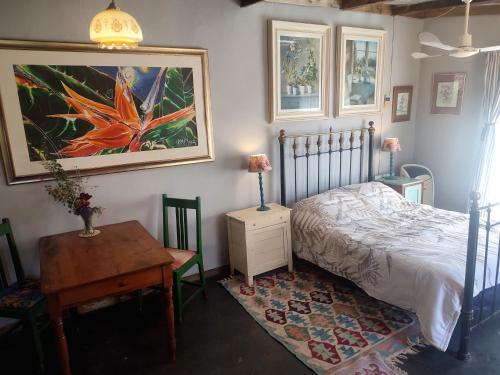 a bedroom with a bed and a table and a painting at Cottage on Roux in Smithfield