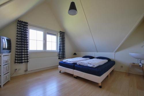 Un dormitorio con una cama y un televisor en un ático. en Beachvilla Luxe met Sauna - 6 personen, en Holle Poarte