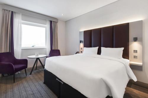a hotel room with a large bed and a chair at Premier Inn Dubai International Airport - An Emirates Group Company in Dubai