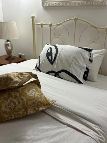 - un lit avec des draps et des oreillers blancs dans l'établissement Valletta apartment, à La Valette