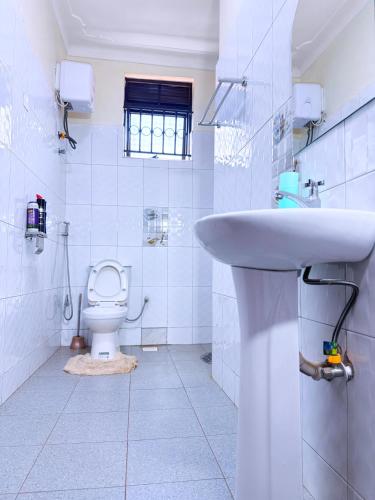 a white bathroom with a sink and a toilet at Seil Apartment in Kampala