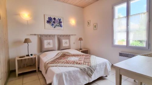 een witte slaapkamer met een bed en een raam bij Au lieu dit La Passe , Villa individuelle de plain pied, avec beaucoup de charme in La Couarde-sur-Mer
