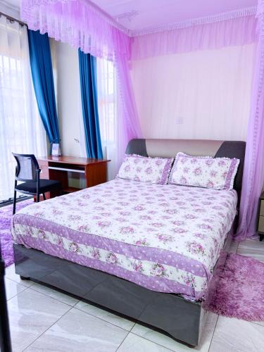 a bedroom with a bed and a desk in it at Seil Apartment in Kampala