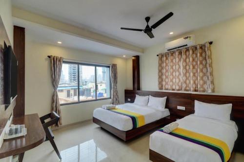 a bedroom with two beds and a desk and a window at Hotel Victoria City Mumbai in Mumbai
