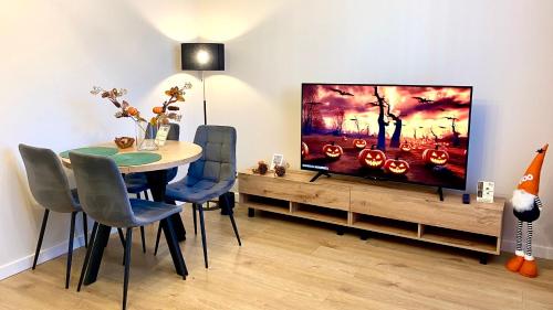 プウォツクにあるApartament GREEN CROWNSのテーブルと薄型テレビのあるダイニングルーム