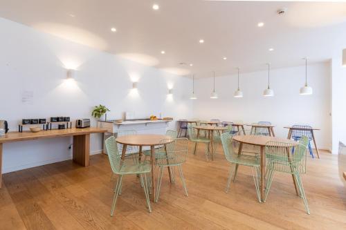 Una habitación con mesas y sillas y una cocina. en Hôtel Porte Mars - Reims Gare Centre Arena, en Reims