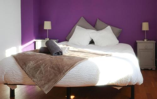 a bedroom with a large bed with a purple wall at La Saint Joseph in Compiègne