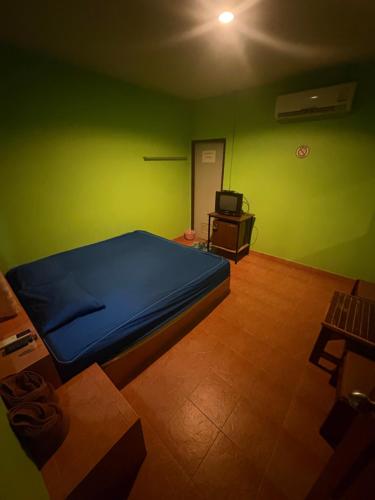 a bedroom with a bed and a green wall at อู๊ดดี้บริการห้องพัก in Nong Prue