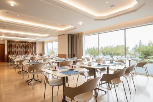 um restaurante com mesas e cadeiras e grandes janelas em Dorma Sardinero em Santander