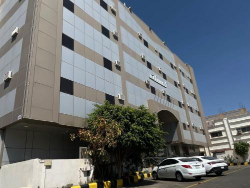 a building with cars parked in front of it at Lamasat Al Ajnaha Serviced Apartments in Abha