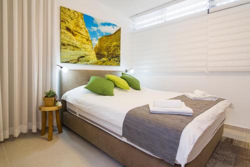 a bedroom with a bed with green pillows at HaBaitBe Matityahu By Domus in Beer Sheva