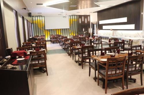um restaurante com mesas e cadeiras de madeira e um ecrã em Hotel Windsor em Patna