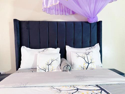 a bed with a black headboard and white pillows at Seil Apartment in Kampala