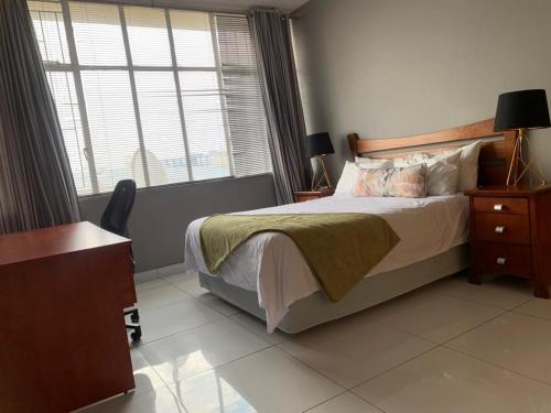 een slaapkamer met een bed, een bureau en een raam bij Moro Rest in Windhoek