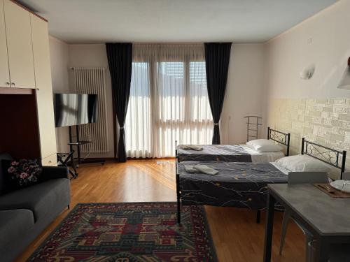 OTB Italia 1 - Luminoso appartamento tra Venezia e Treviso con Terrazza e Posto auto Coperto في بريغانزيول: غرفة معيشة بها سريرين وأريكة