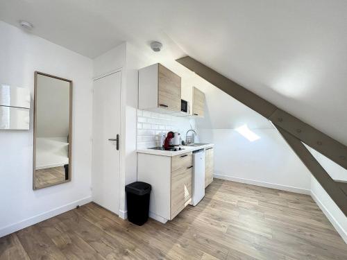 eine weiße Küche mit einer Spüle und einer Theke in der Unterkunft Studio Le Cesson sous les toits - Proche gare in Saint-Brieuc