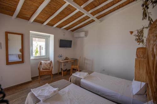 a room with two beds and a table and a mirror at Vinhas Douradas in Moura