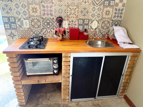 a small kitchen with a microwave and a sink at chalé encanto dos milagres in São Miguel dos Milagres
