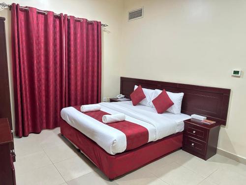 a bedroom with a large bed with red curtains at Al Reem Hotel Apartments in Sharjah