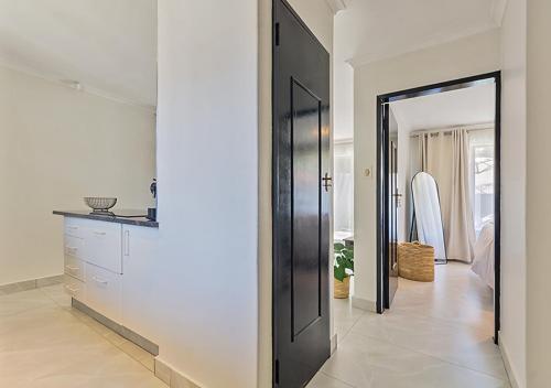 einen Flur mit schwarzer Tür und ein Schlafzimmer in der Unterkunft Pristine Modern Cottage with Tennis & Laundry in Johannesburg