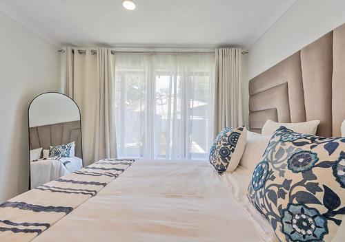ein Schlafzimmer mit zwei Betten und einem großen Fenster in der Unterkunft Pristine Modern Cottage with Tennis & Laundry in Johannesburg