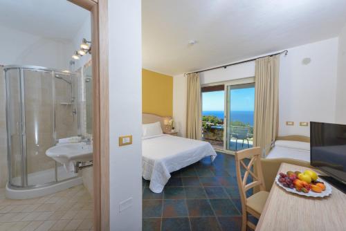a hotel room with a bathroom with a bed and a sink at Castelsardo Resort Village in Castelsardo