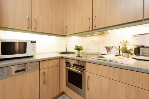 a kitchen with wooden cabinets and a microwave at Strandhaferweg 7 Möwenoase in Burgtiefe auf Fehmarn 