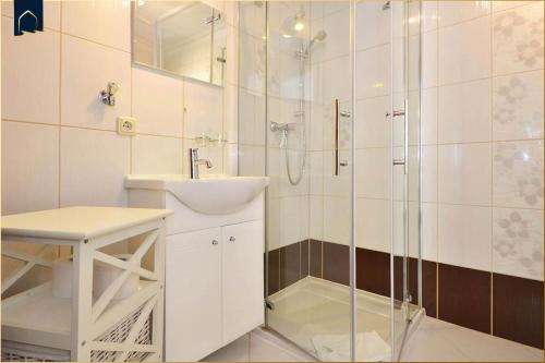 een witte badkamer met douche en wastafel bij Haus Lindenstraße (051) An den Linden in Heringsdorf