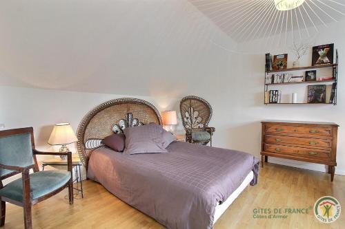 a bedroom with a bed and a chair and a dresser at De rulinen in Saint-Clet