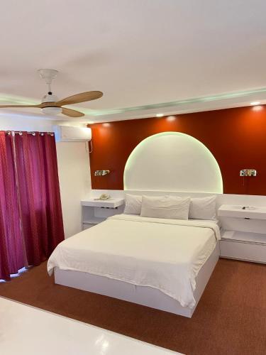a bedroom with a white bed and a red wall at Buena Casa Hotel in Olongapo