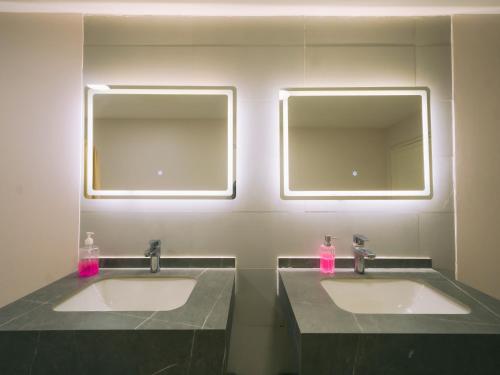 two sinks in a bathroom with two mirrors at Palm Escape Farmhouse - By Seven Elements in Ras al Khaimah