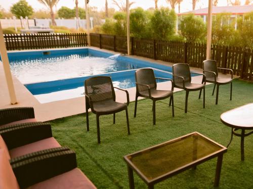 a group of chairs and tables in front of a pool at Palm Escape Farmhouse - By Seven Elements in Ras al Khaimah