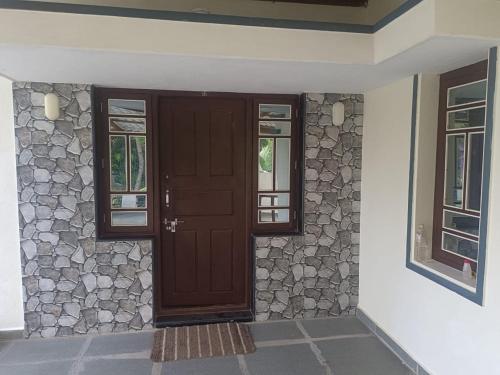 een voordeur van een huis met een stenen muur bij White House Home Stay! in Kaup
