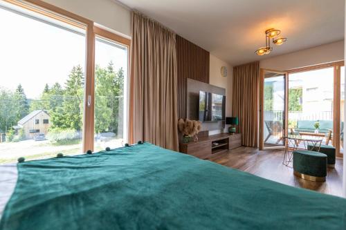 a bedroom with a large green bed and large windows at Apartmán Esprit Y31 in Dolný Kubín