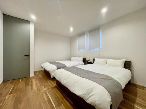 deux lits dans une chambre avec deux fenêtres dans l'établissement Lohas Resort 芥屋A, à Itoshima